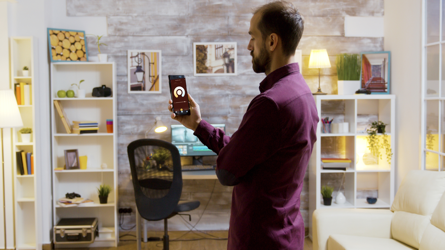 Hombre mira su teléfono móvil con el que control las luces de su casa de manera inteligente